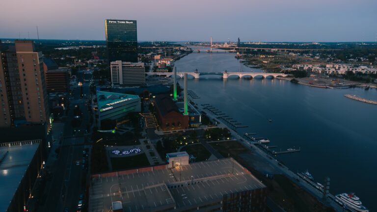 Drone controller hands close drone aerial cityscape river