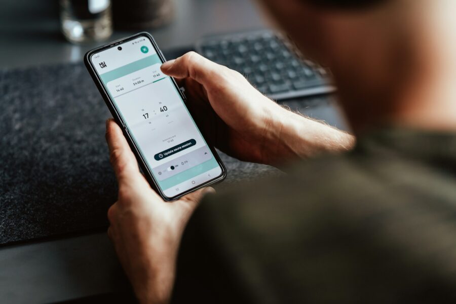 Hand holding phone item tracker keys table