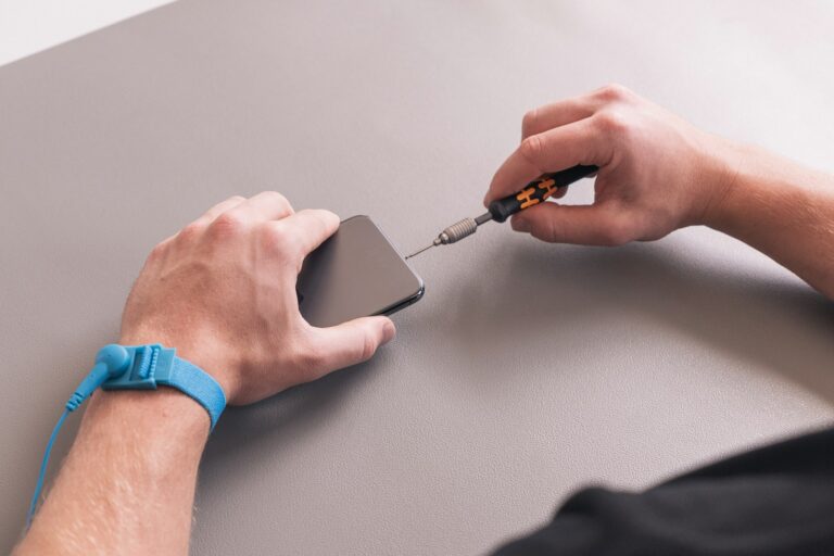 Hand holding phone item tracker keys table
